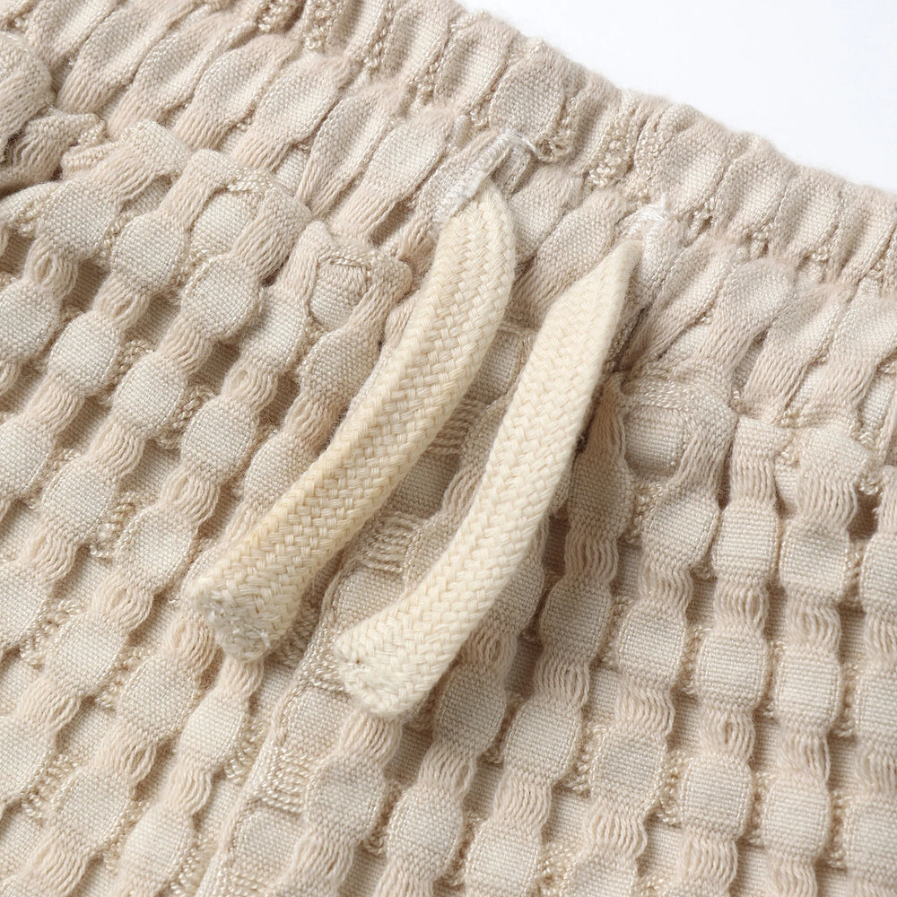 
                      
                        Close-up of Quincy Mae Flynn Set shorts, featuring chunky waffle texture and adjustable tie waist for a comfortable baby fit.
                      
                    