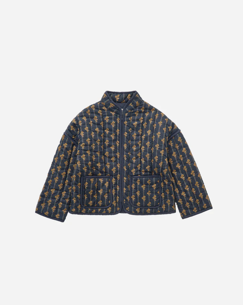 Flatlay of the Rylee + Cru Quilted Jacket in Vintage Bloom, showing soft navy floral print with contrast binding and front pockets, displayed on a light background for detail clarity.