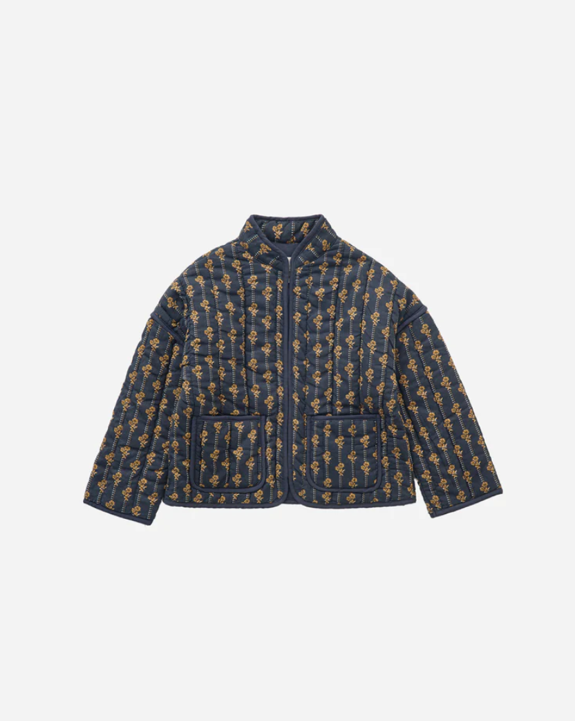 Flatlay of the Rylee + Cru Quilted Jacket in Vintage Bloom, showing soft navy floral print with contrast binding and front pockets, displayed on a light background for detail clarity.