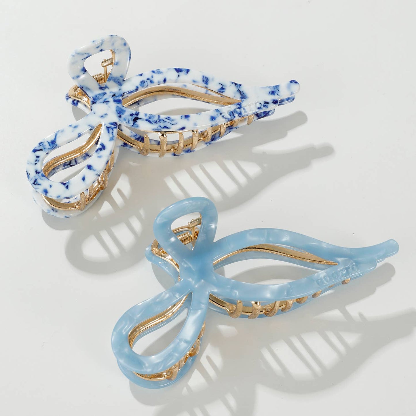 Two biodegradable blue and gold hair clips on a white background - Coastal Blue & White and Saltwater Blue