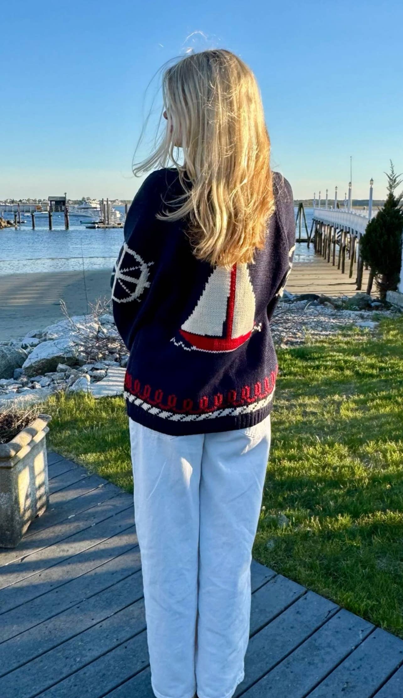 Woman wearing sailboat knit cardigan styled casually for breezy coastal day