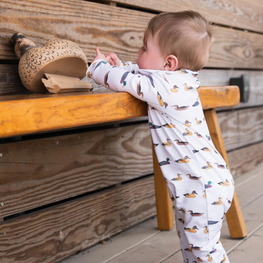 Baby in SBC Signature Polo Long-Sleeve Romper standing with a duck decoy, showcasing durable, comfortable design perfect for active babies.