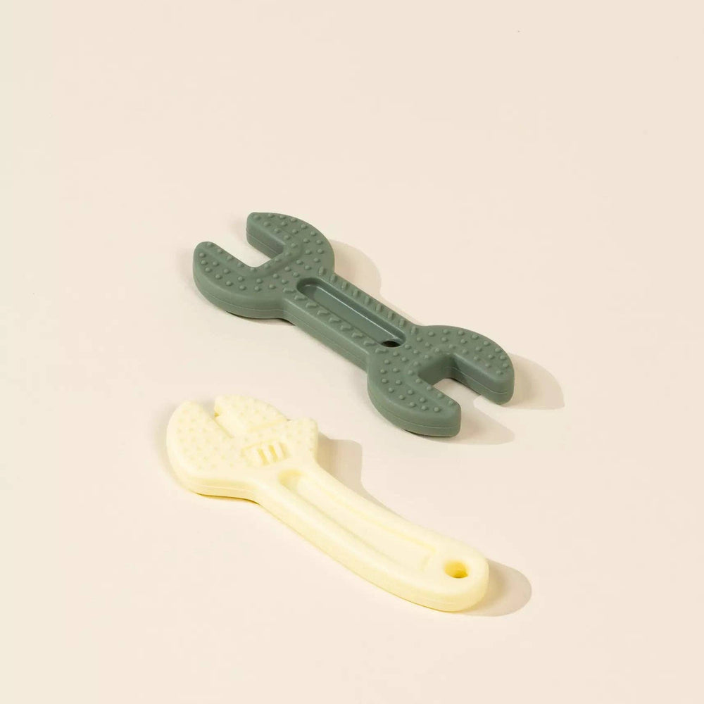 
                      
                        Flatlay of two silicone baby toys shaped like tools in soft, neutral colors, designed for sensory play and safe teething.
                      
                    