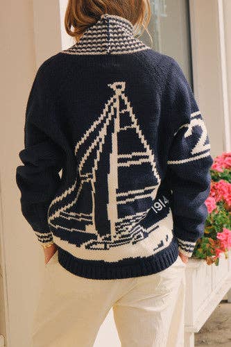 Model wearing the navy sailboat varsity cardigan with hands in pockets, displaying the full back sailboat motif.