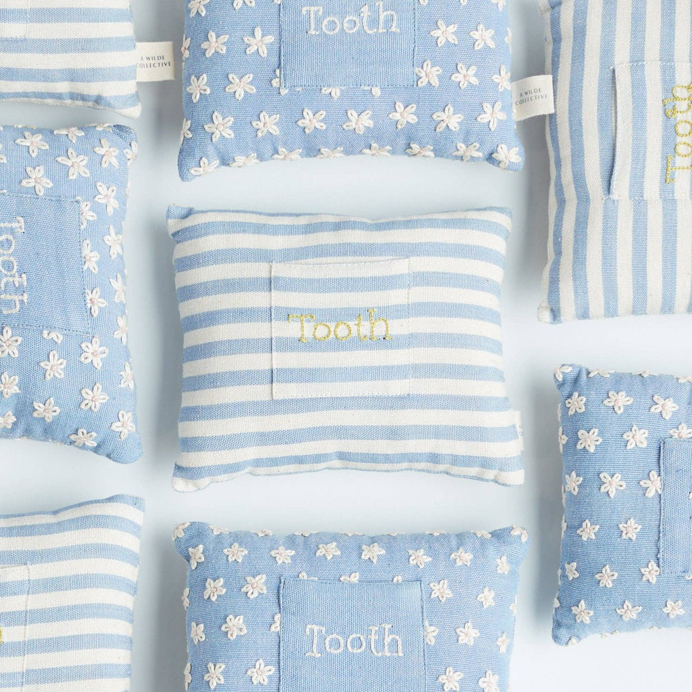 
                      
                        Flat lay of the front side of the striped tooth fairy pillow with hand-embroidered detail and front pocket alongside floral version
                      
                    