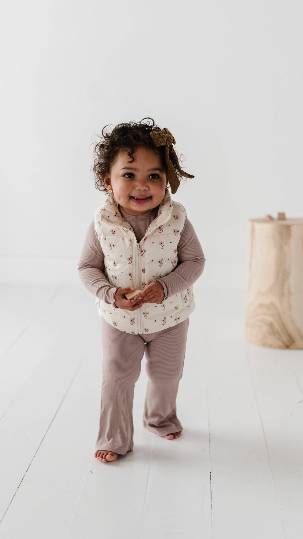 Toddler wearing lilac lettuce hem tee layered with puffer vest, combining style and warmth for a cozy, practical fall outfit.