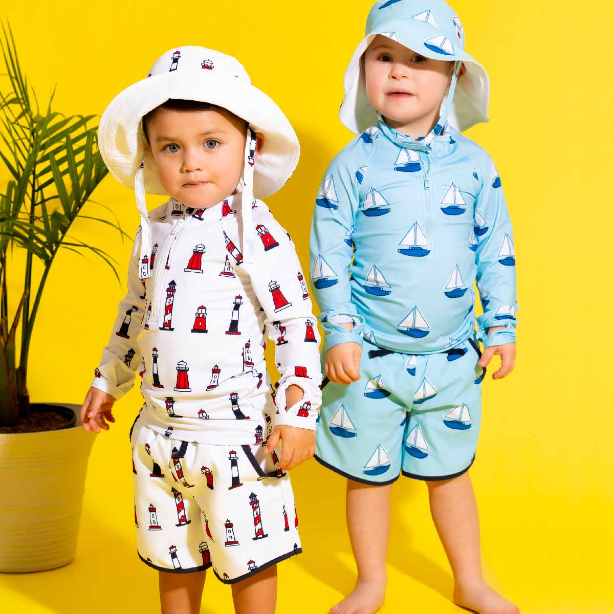 Two children in coordinating summer outfits wearing Set Sail UPF 50+ sun hats near pool or beach