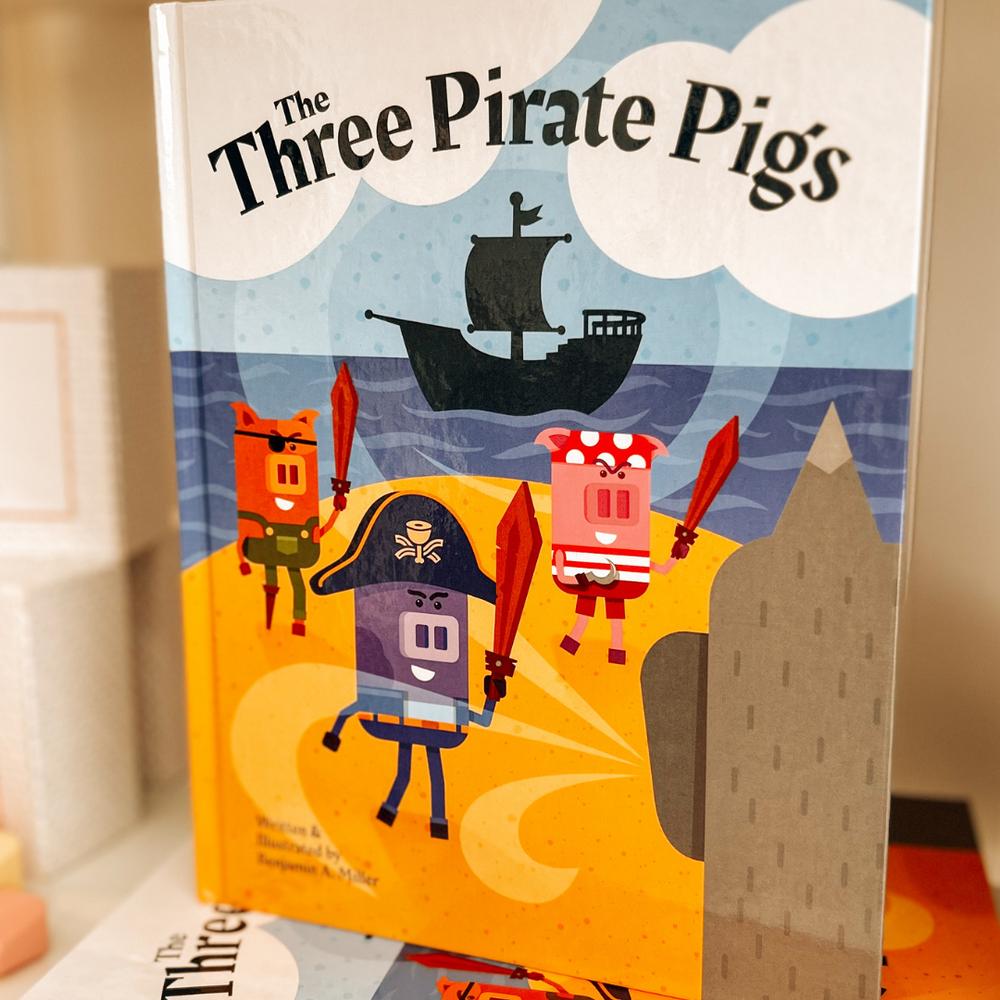 
                      
                        “The Three Pirate Pigs” children’s book displayed on a shelf at Grace & Haven in Essex, CT, featuring its whimsical cover illustration of the three pirate pigs.
                      
                    