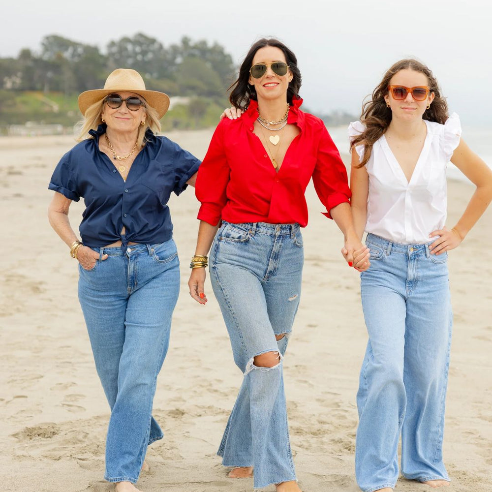
                      
                        Three women of all ages walking side by side on the beach toward the camera—one wearing the KMJ Quarantini in navy, one in the Southern Lover in red (Kate, the designer), and one in the Olivia in white.
                      
                    