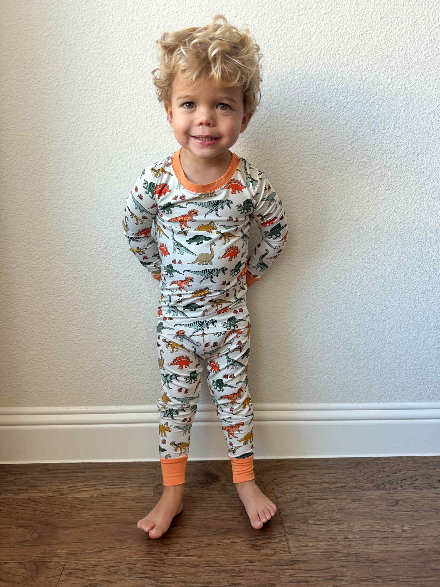 Toddler lounging in organic dinosaur pajamas, breathable and gentle on skin
