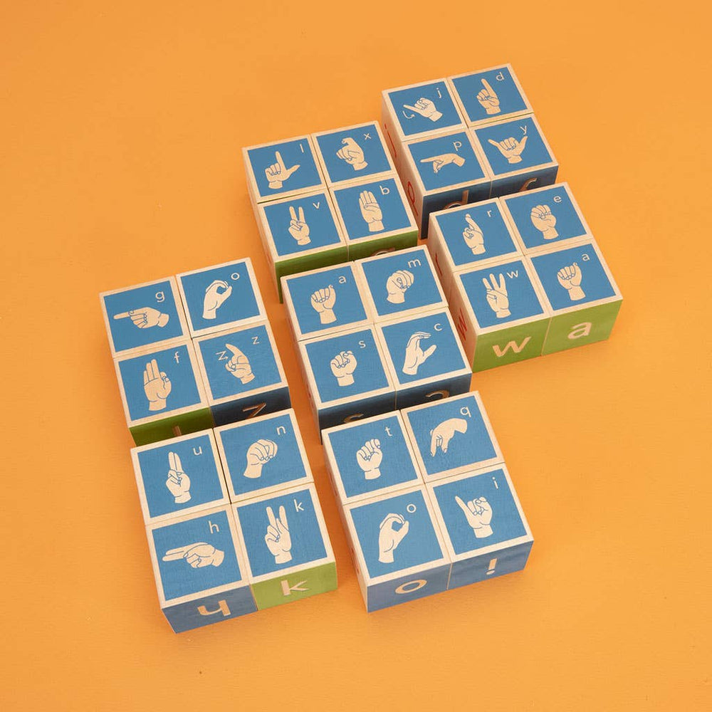 Flatlay of Uncle Goose ASL blocks displaying the sign language symbol side of each wooden cube for early language learning