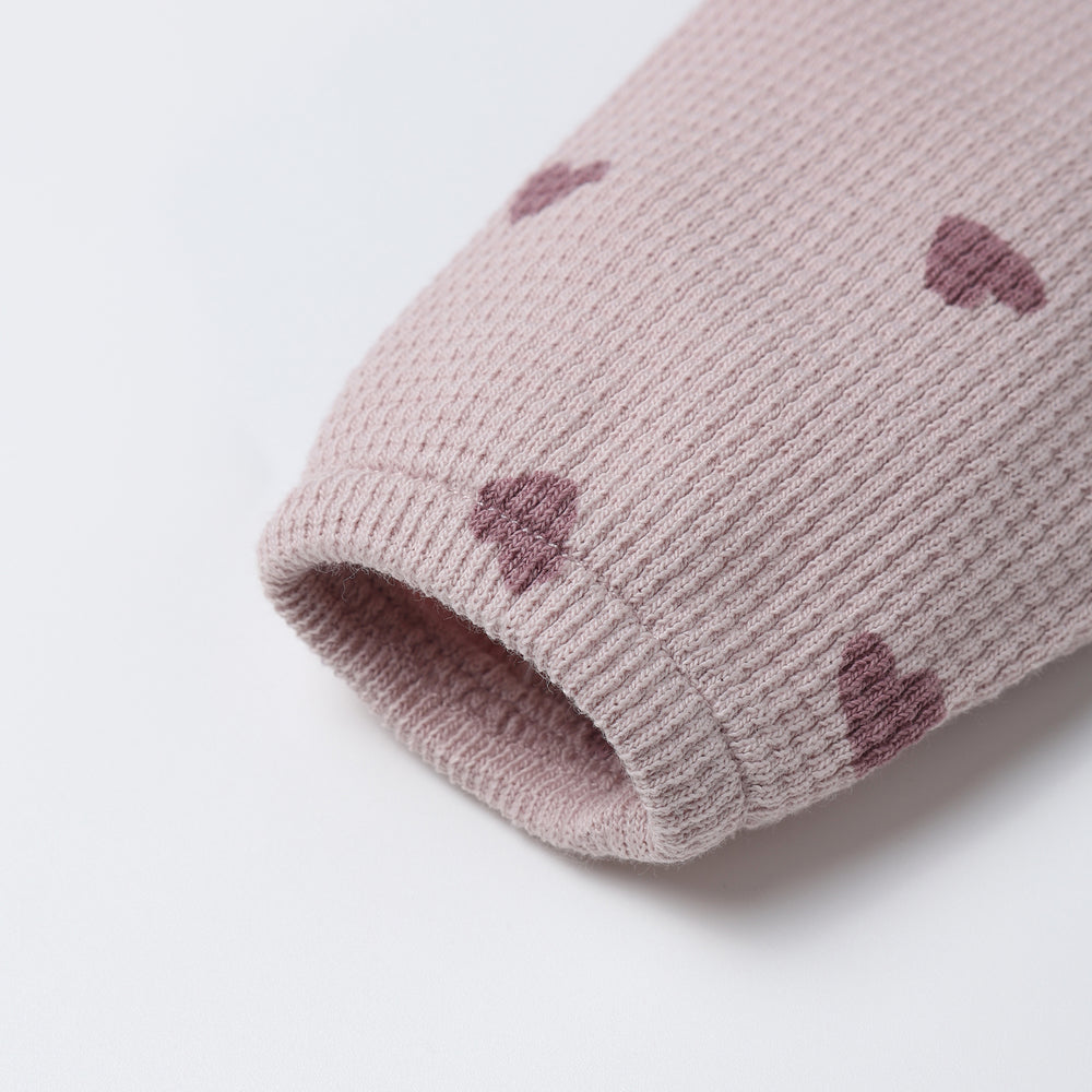 Close-up of heart print and hidden snap details on the Waffle Long Sleeve Jumpsuit by Quincy Mae.
