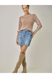 Blush pink cable mock neck sweater styled with a denim skirt and tall boots
